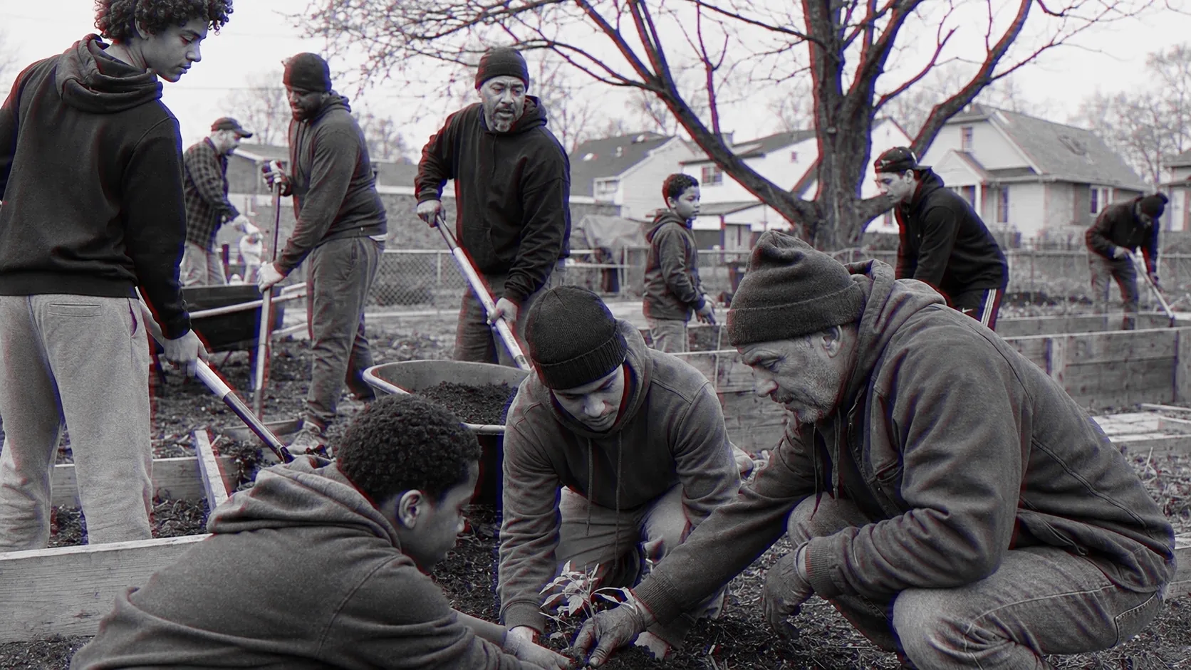 Neighbours of three generations turn beds in a community garden, a boy working beside them.